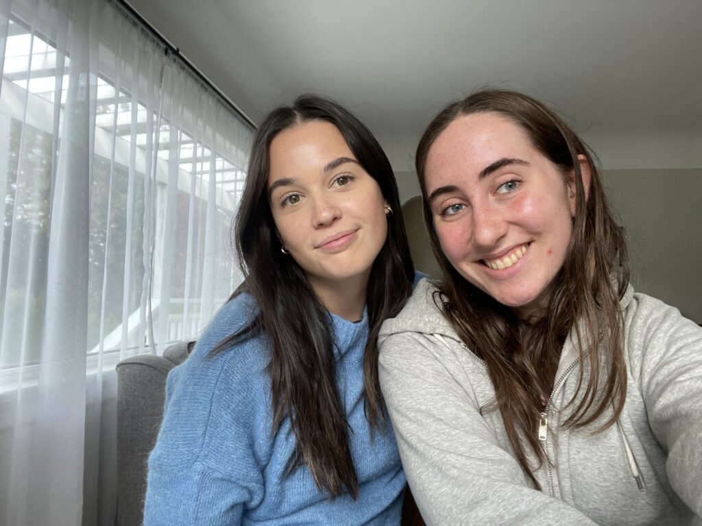 Two beautiful girls smiling together in a living room. 